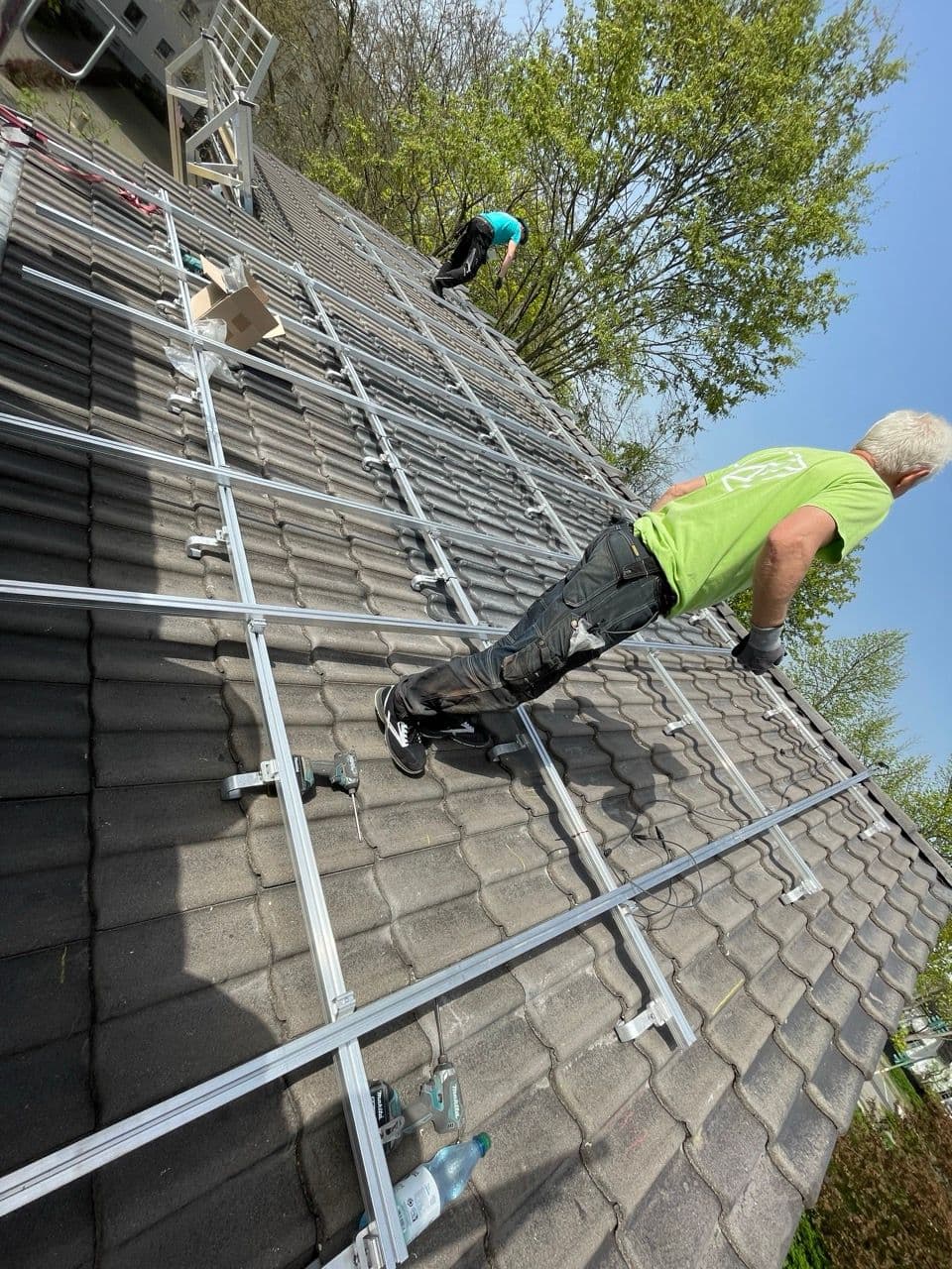 Montageschienen für PV-Module auf einem Ziegeldach. Mitarbeiter von sunday solar sind zu sehen